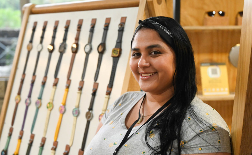 Melany Bolívar Foto de la artesana Melany Bolivar y al fondo, se ven los relojes artesanales que se elaboran en su taller