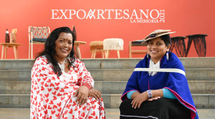 Fotografía de las artesanas Adeinis Boscan y Patricia Hurtado, quienes hicieron parte de la feria, sentadas en unas escaleras y con la marca Expoartesano.