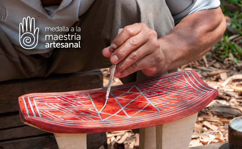 Programa Medalla a la Maestría Artesanal Fotografía de manos pintando un banco pensador elaborado en madera