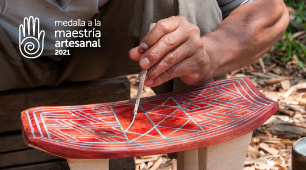 Fotografía de manos pintando un banco pensador elaborado en madera