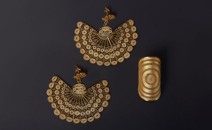 Foto de un par de aretes y un anillo elaborados en la técnica de filigrana de Mompox