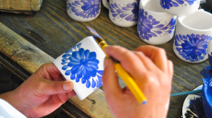 Manos pintando una taza elaborada en cerámica de El Carmen de Viboral