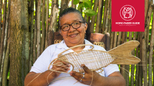 Foto de la artesana Edilsa Baldomino tejiendo una artesanía con forma de pescado en fibra de iraca